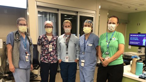 Photo of five female health care workers standing in front of a desk in a medical facility and wearing Crocs received through the company's campaign for frontline workers.