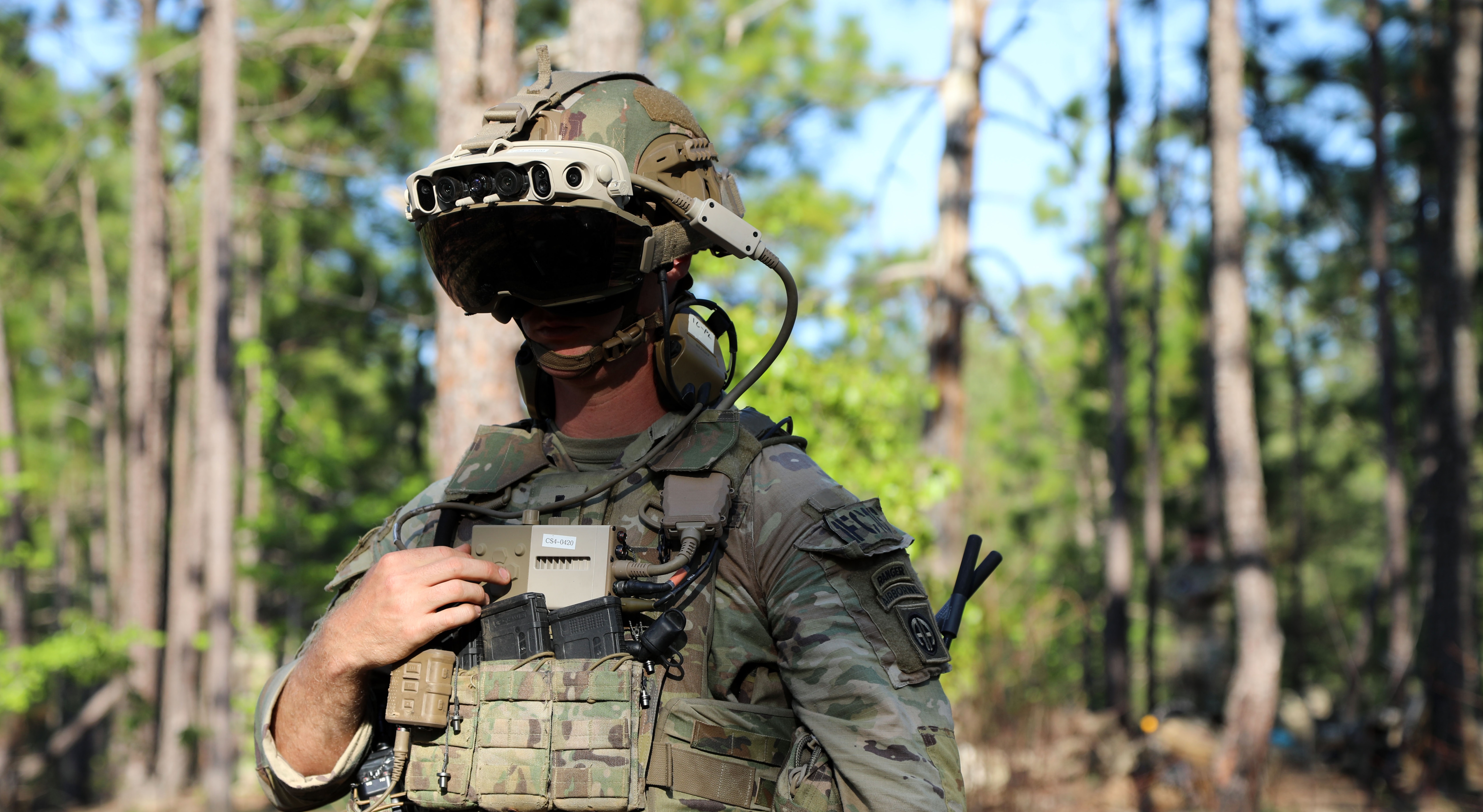Photo of a soldier in a wooded area, wearing a mixed-reality headset during testing.