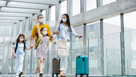 A family wearing face coverings walks through an airport