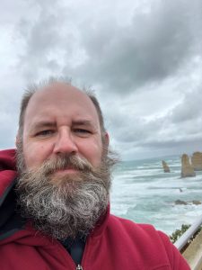 Head and shoulders photo of ERDC research mathematician Chris Massey with a windswept beach in background.