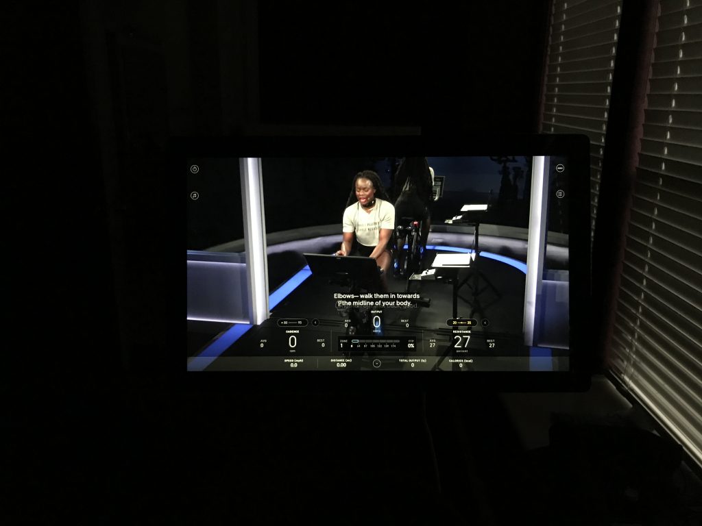 Close-up photo showing a Peloton Bike screen and an instructor with live subtitling.