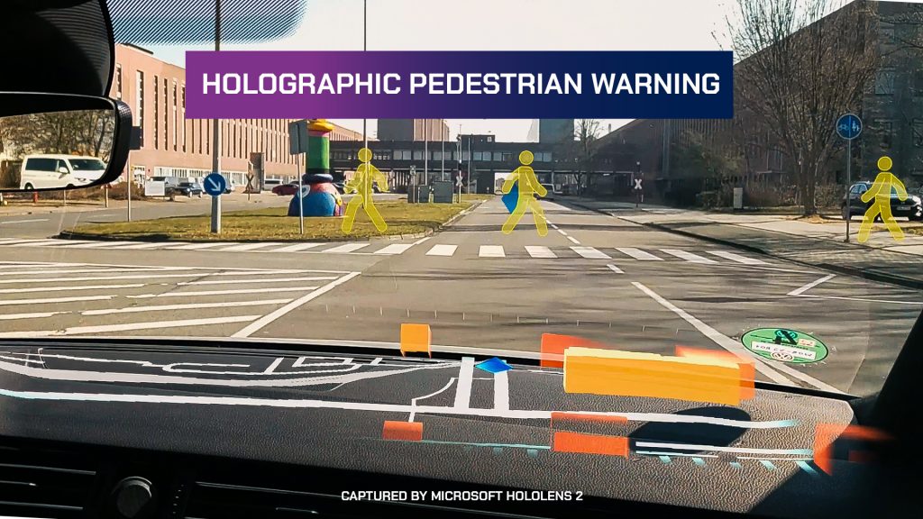 Foto scattata all'interno di un'auto che mostra le immagini di navigazione sovrapposte al parabrezza tramite l'uso di HoloLens.