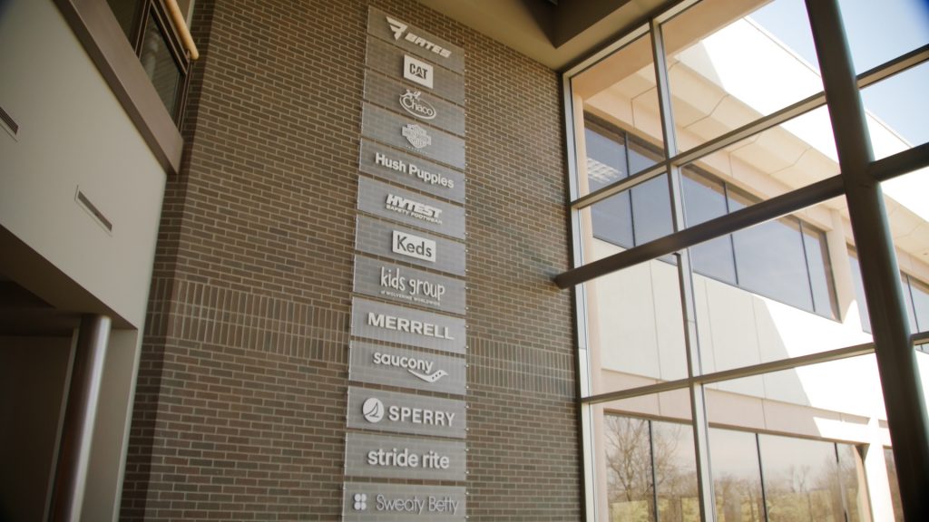 Wolverine Worldwide's brands are listed by name on a vertical wall display.
