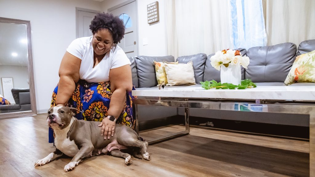 Portrait of MARTA Reach user LaQuetta Ferrell smiling and sitting on her couch at home with her dog Molly at her feet.