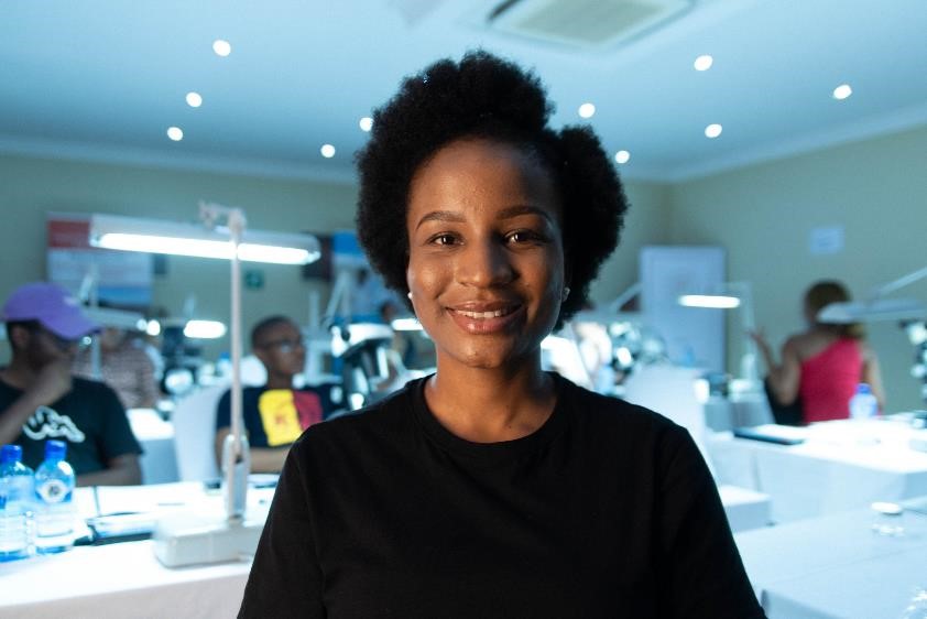 Photo of smiling young woman working at a diamond processing facility.