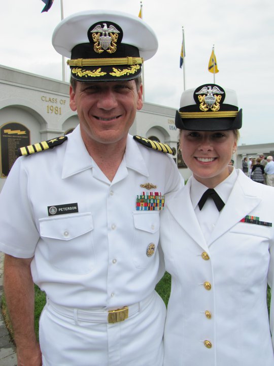 man in naval uniform smiles with his daughter, also in naval uniform