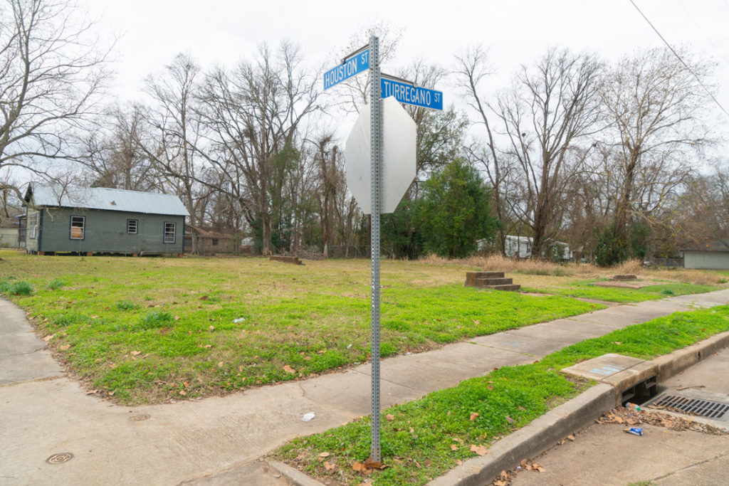  A photo of a grassy lot with road signs that read Houston Street and Turregano Street