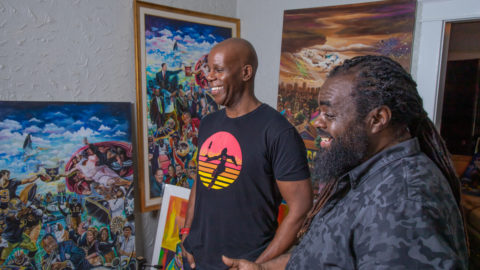 A phooto of Howard Robinson and Richard Thomas laughing and smiling while looking at art pieces in Thomas' New Orleans studio.