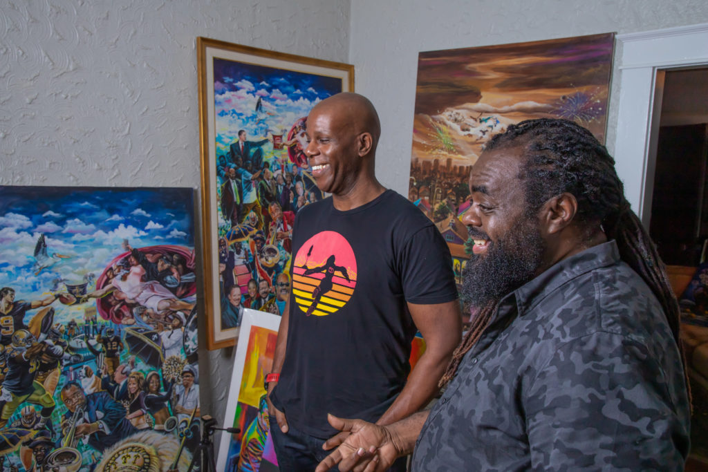 A phooto of Howard Robinson and Richard Thomas laughing and smiling while looking at art pieces in Thomas' New Orleans studio.