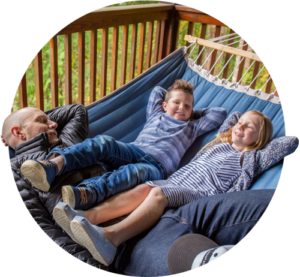 A man and his two kids, a boy and a girl, lie in a hammock