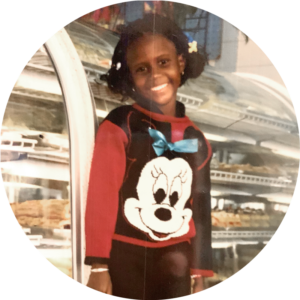 A young girl standing in front of a pastry case wearing a Minnie Mouse sweatshirt