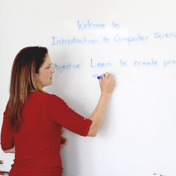 A woman writing on a white board with a blue marker