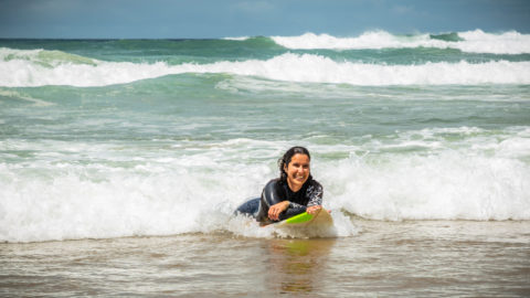 a photo of a woman laying down on her surfboard in the ocean waves
