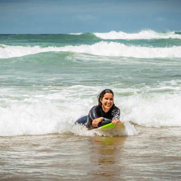 a photo of a woman laying down on her surfboard in the ocean waves