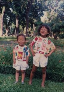 Two children stand in a park while wearing matching outfits. The author of the story is pictured on the left.