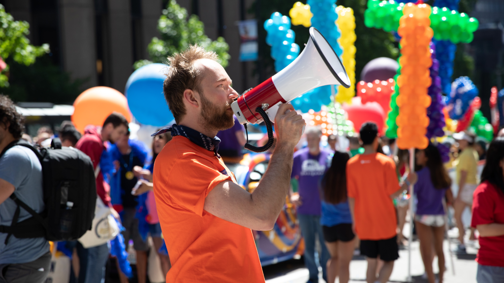 Aleksey speaking into a megaphone at a Pride rally.