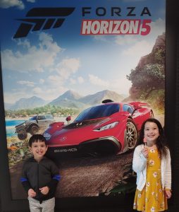 Luis's children standing in front of a Forza Horizon 5 poster.