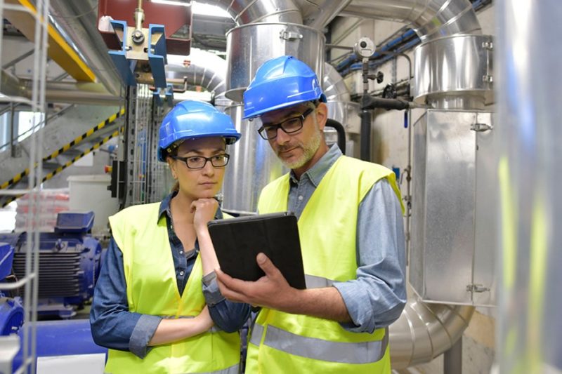two people in hard hats consult a tablet
