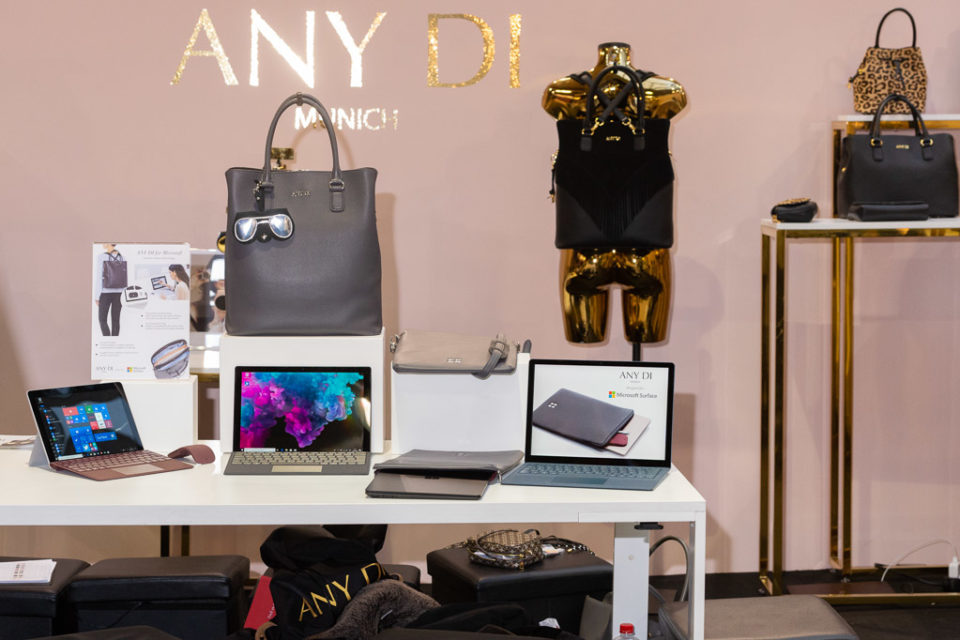 Das Bild zeigt den ANY DI Stand auf der PREMIUM während der Berlin Fashion Week 2019. Auf dem Bild sind im Hintergrund die Taschen von ANY DI zu sehen, während im Vordergrund Surface Pro 6 und Surface Laptop 2 aufgereiht sind.