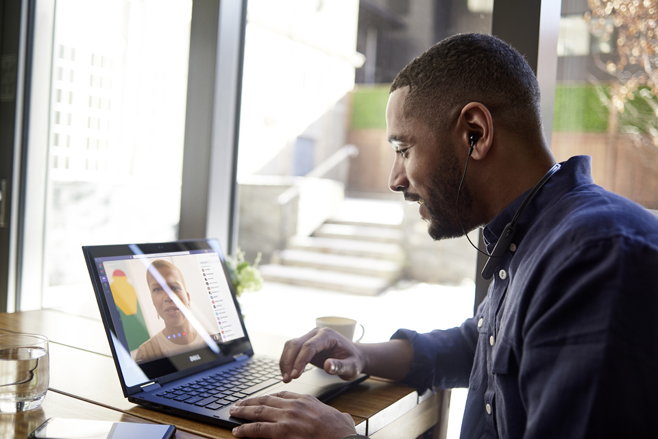 Ein Mann sitzt an einem Tisch und hält über seinen Laptop eine Videobesprechung mit Microsoft Teams ab.