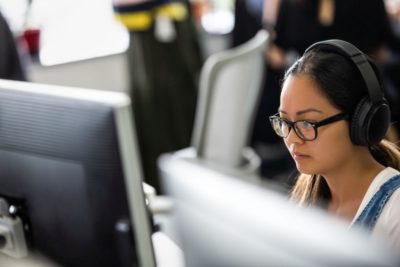 Eine Frau mit Brille sitzt vor dem Computer und leistet Support