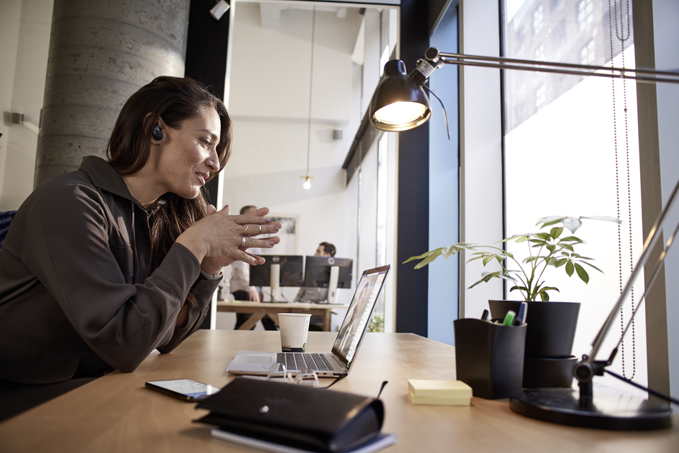 Eine Frau sitzt am Schreibtisch und nutzt Videobesprechungen in Microsoft Teams.