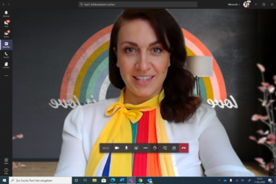 Screenshot eines Microsoft Teams Call; Magdalena Rogl in Regenbogenbluse, im Hintergrund ein Regenbogen