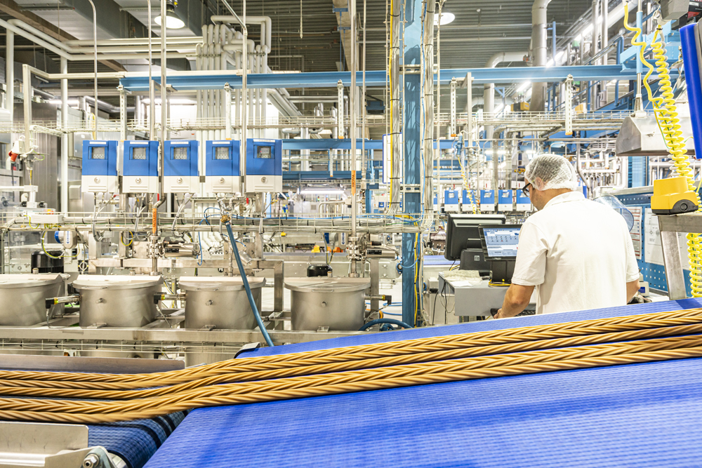 Zu sehen ist eine Produktionshalle von RONDO FOOD, in der ein Produktionsmitarbeiter arbeitet.