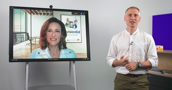 Der Sprecher Michael Wittel steht neben einem Surface Hub, auf dem Barbara Holzapfel in einer Video-Konferenz zu sehen ist