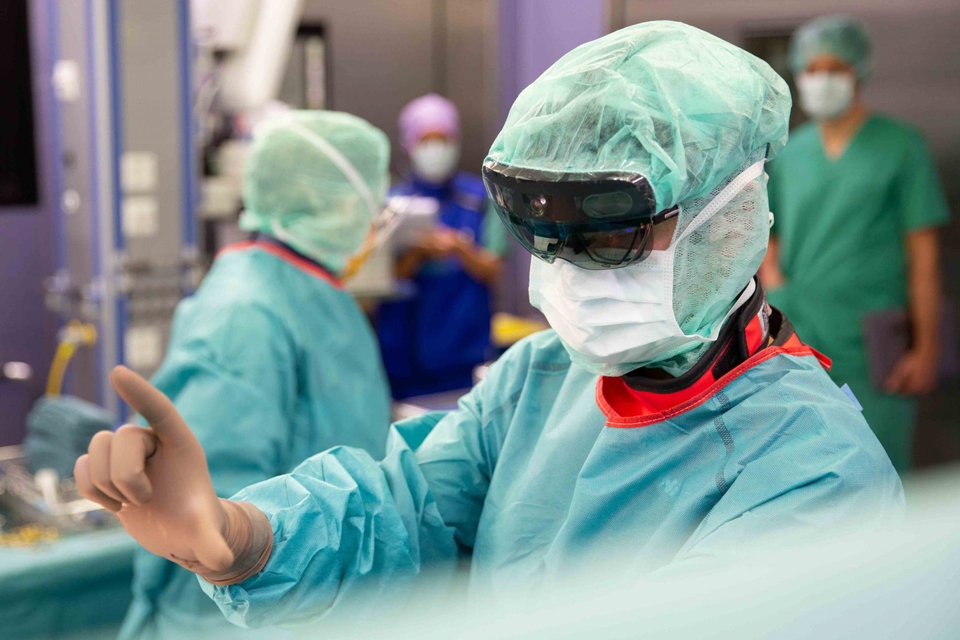 Arzt im OP-Saal trägt die Hololens und steuert sie mit den Fingern