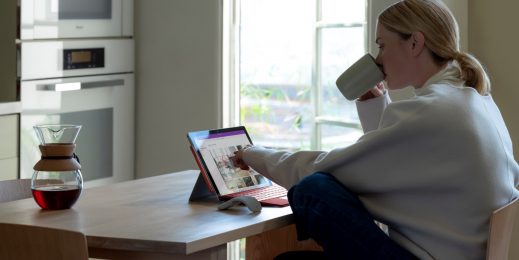 woman sitting in front of her surface with a coffee in her hand
