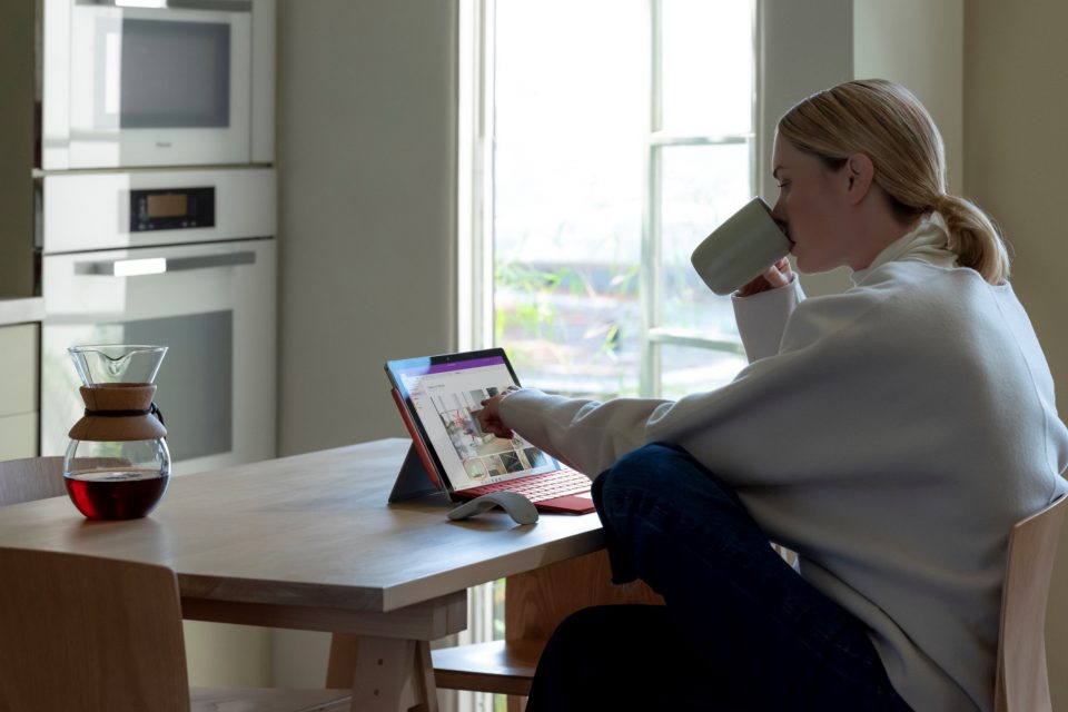woman sitting in front of her surface with a coffee in her hand