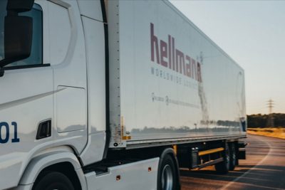 Front und Seite eines Lastwagens von Hellmann Logistics, auf einer Straße