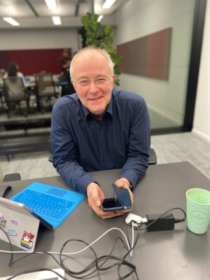 Thomas Langkabel am Arbeitsplatz mit Smartphone in der Hand