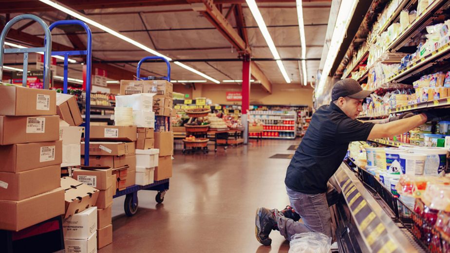 Mann räumt Artikel in ein Supermarktregal