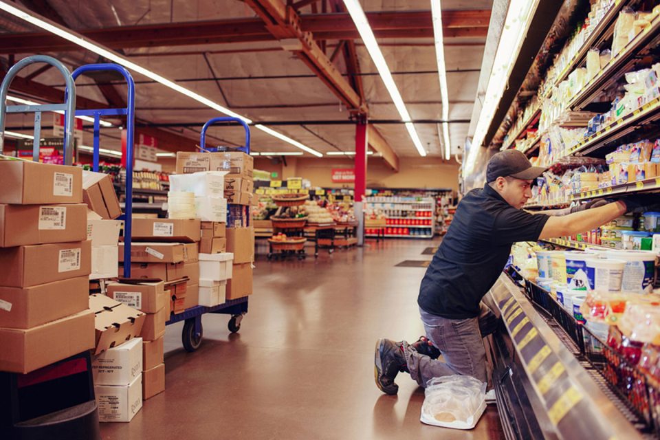 Mann räumt Artikel in ein Supermarktregal