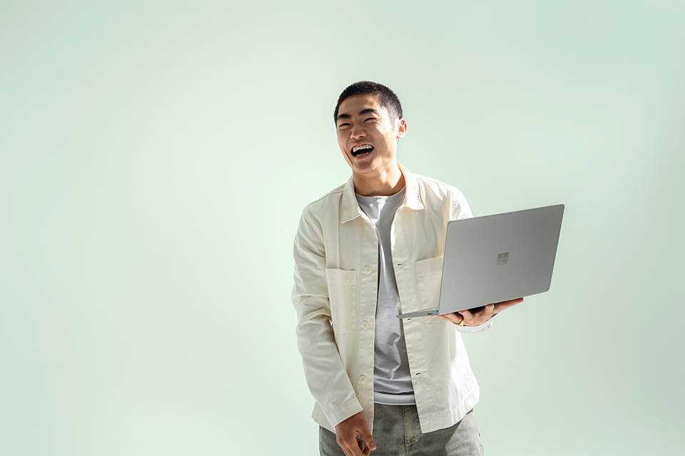 Mann hält Surface Laptop Go 2 in der Farbe salbei in der Hand
