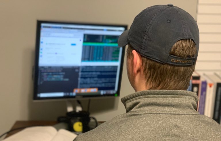 Un hombre con una gorra mira una pantalla de computadora