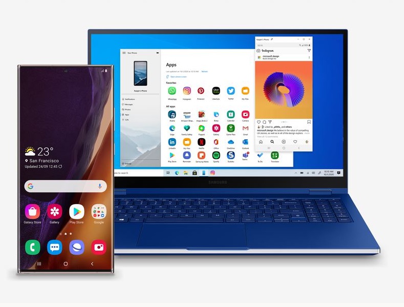 Teléfono Samsung junto a una laptop abierta con un teclado azul.