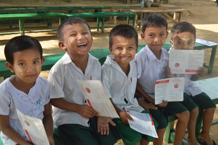 Foto de un grupo de jóvenes en Myanmar, que sonríen y muestran sus certificados de vacunación.