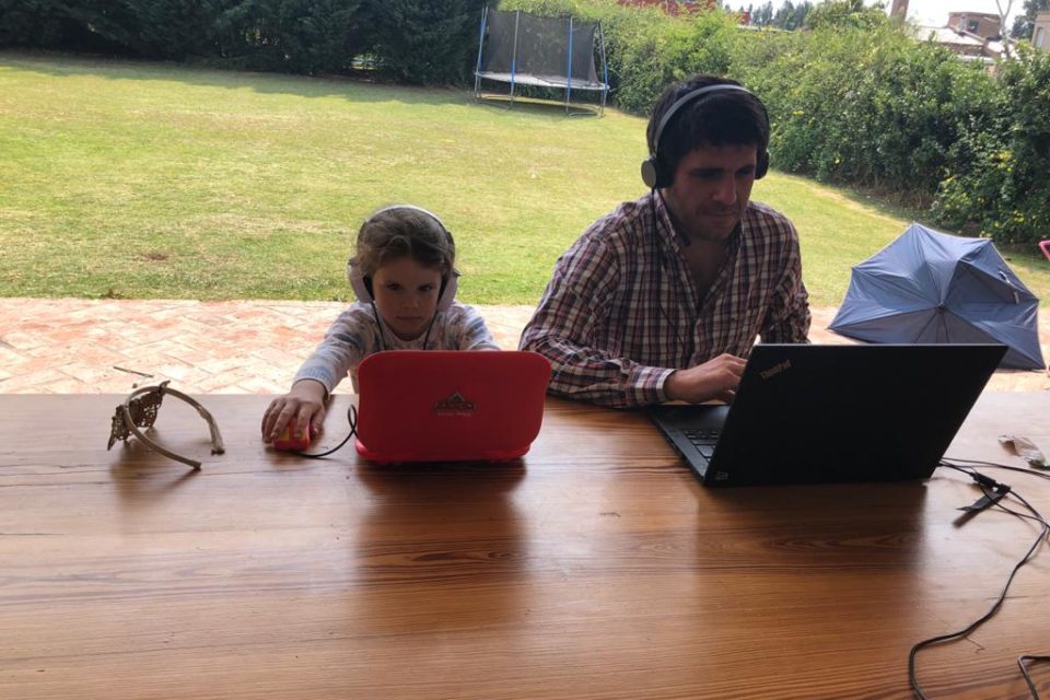 Hombre y un niño sentados frente a sus laptops