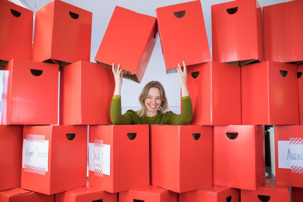 Una mujer de pie en medio de una pila de cajas rojas
