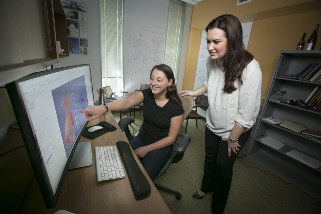 Amanda Randles y una colega colaboran en una computadora.