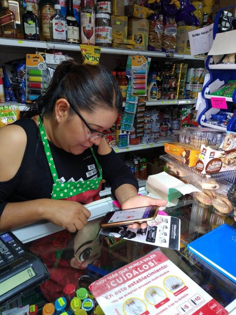 Una mujer detrás de un mostrador en una tienda sostiene un smartphone