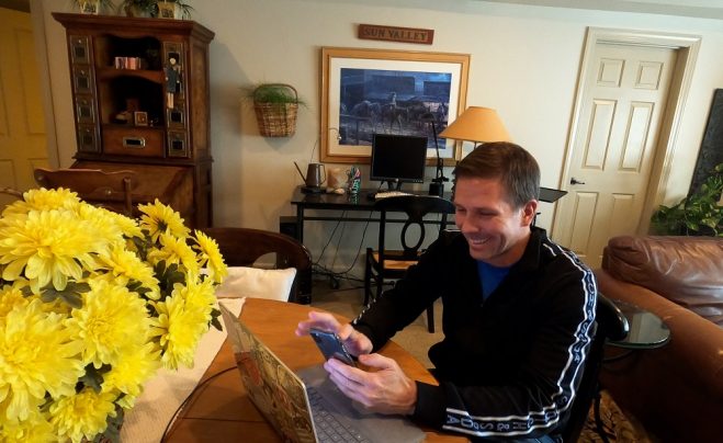Un hombre trabaja desde su teléfono y laptop en casa