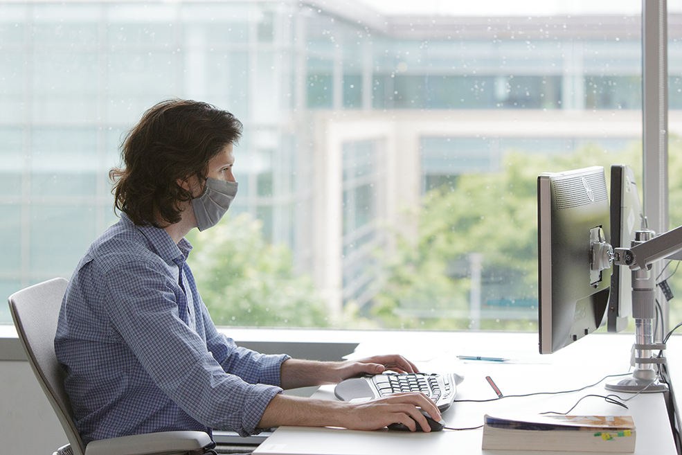 Un hombre sentado frente a un escritorio trabaja en una laptop