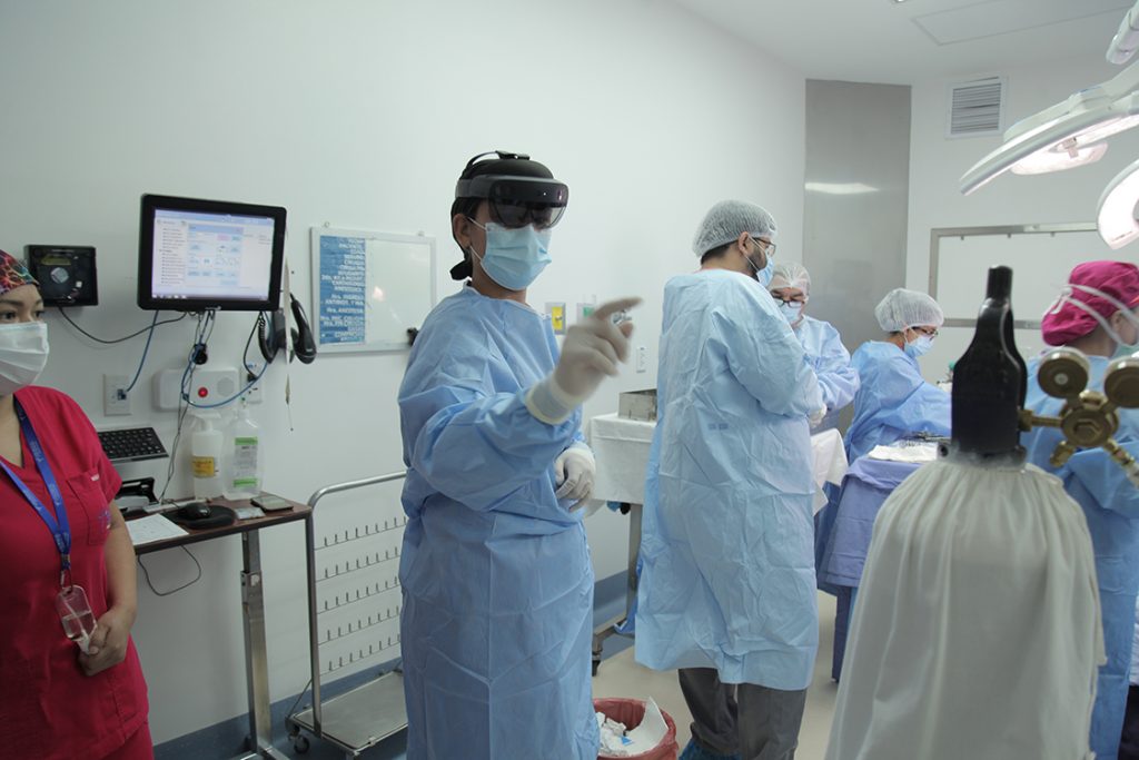 Una mujer usando equipo médico interactúa con HoloLens 2