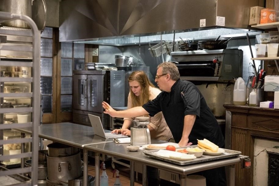 Dos personas trabajan en una laptop en la cocina de un restaurante