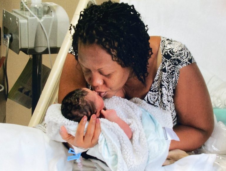 Una madre besa a su hija recién nacida en el hospital.