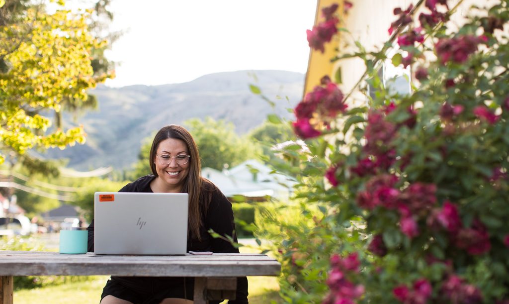 Una mujer trabaja en una laptop en un jardín